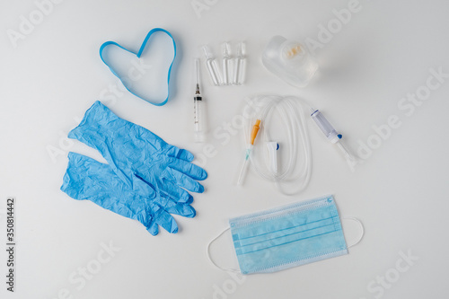 Medical protection on a white background top view. Intravenous system, syringes, gloves, mask and tourniquet in the form of a heart. Treatment of a coronovirus pandemic in the country.