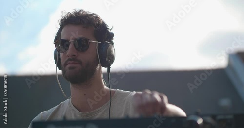 young man is playing a DJ set at a rooftop