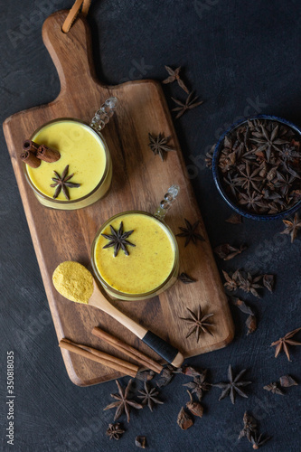 Top view of golden milk with turmeric powder on wooden board