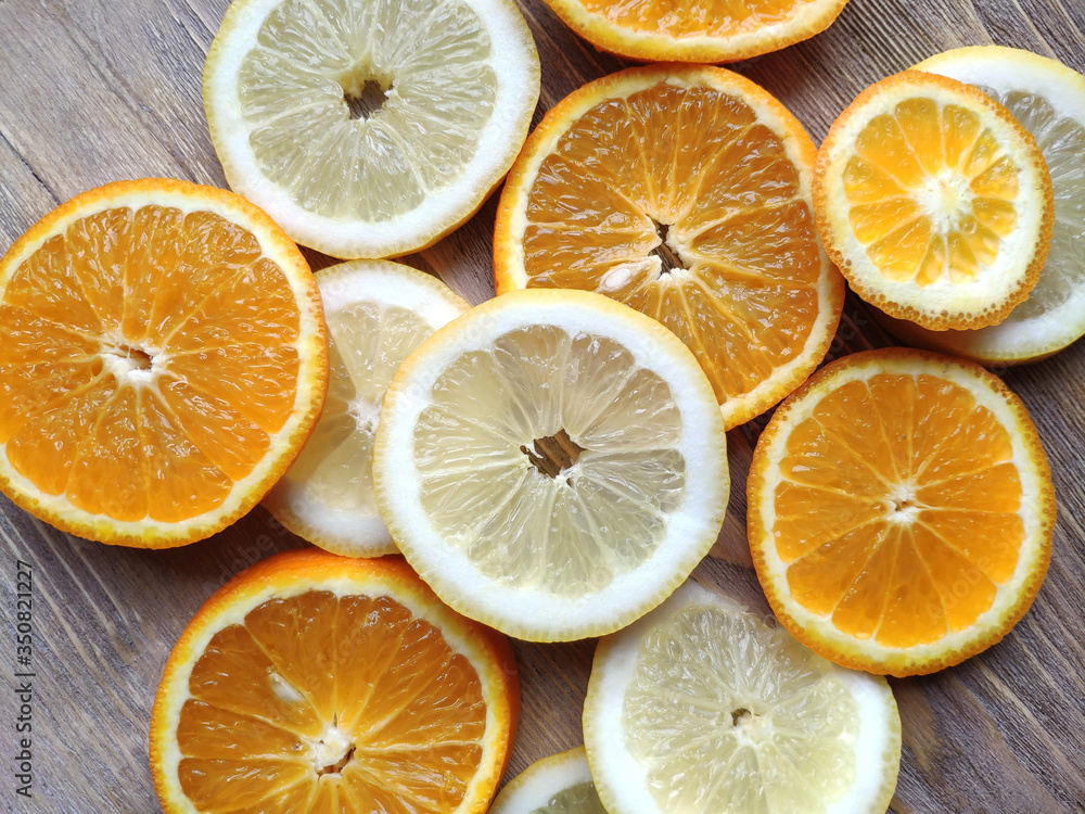 Slices of fresh juicy lemon and oranges on a wooden table. Healthy wholesome food. Vegan food Slices of fresh juicy lemon and oranges on a wooden table. Healthy wholesome food. Vegan food