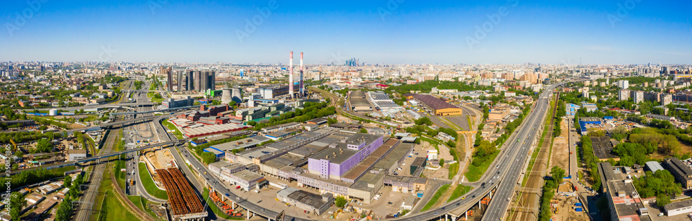 Power plant pipes and cooling towers in Moscow from above, automobile traffic and and construction of a new car overpass and interchange in the Moscow industrial zone near the automobile ring highway