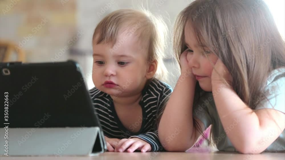 the kids are watching cartoons on the tablet. Family time, vacation. The concept of homework, quarantine, self-isolation, protection from coronavirus, virus, home education, distance work, training the kids are watching cartoons on the tablet. Family time, vacation. The concept of homework, quarantine, self-isolation, protection from coronavirus, virus, home education, distance work, training