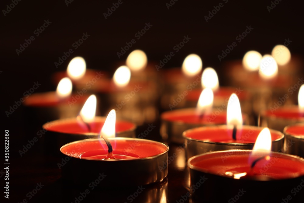 Close-Up Of Candles Burning On Table Against Black Background