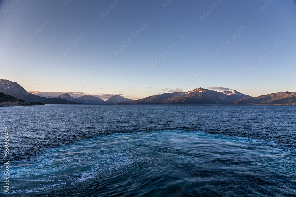 A mystical fjord in Norway with mountains and fog hanging over the water in polar day. midnight sun, selective focus A mystical fjord in Norway with mountains and fog hanging over the water in polar day. midnight sun, selective focus