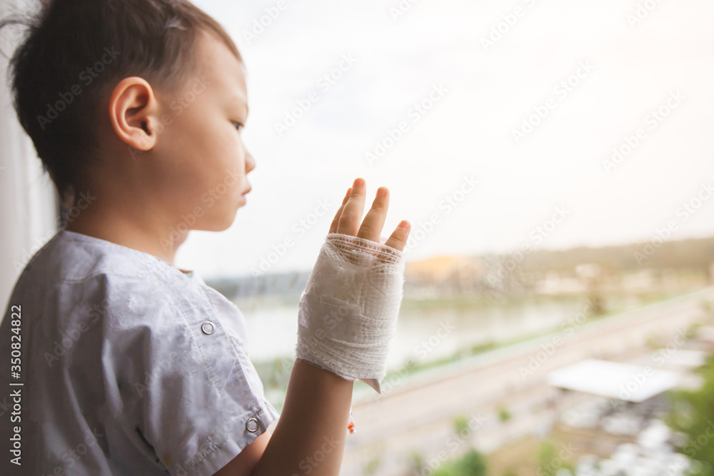 Sick asian child boy at the hospital looking outside through the window and want to go home Sick asian child boy at the hospital looking outside through the window and want to go home