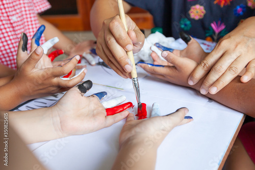 Parent is painting on children s hands with watercolor with fun. Family doing activity when stay at home quarantine from the coronavirus Covid-19.