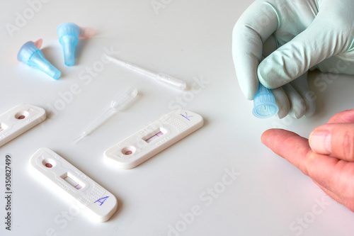 Rapid COVID-19 test for detection of specific antibodies IgM and IgG to novel corona virus SARS-CoV-2 causing Covid-19 illness. Medic or doctor in protective gloves is about to pick patient finger.