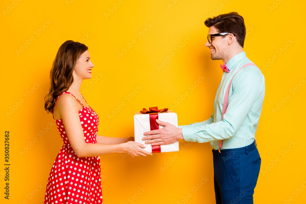 Profile photo of pretty lady handsome guy couple boyfriend giving girlfriend big gift box 8 march present wear red dotted dress shirt bowtie pants isolated yellow bright color background Profile photo of pretty lady handsome guy couple boyfriend giving girlfriend big gift box 8 march present wear red dotted dress shirt bowtie pants isolated yellow bright color background