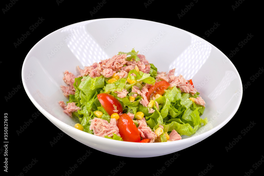 Tasty salad with tuna, lettuce, tomatoes and corn in a white plate, isolated on black background Tasty salad with tuna, lettuce, tomatoes and corn in a white plate, isolated on black background