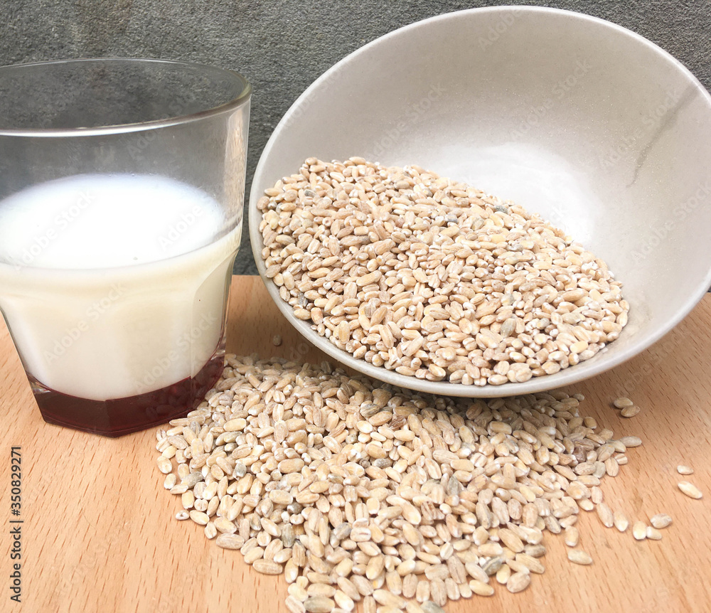 glass of milk and pearl barley porridge on a wooden table milk in a glass in the morning in the village with cereal for breakfast glass of milk and pearl barley porridge on a wooden table milk in a glass in the morning in the village with cereal for breakfast