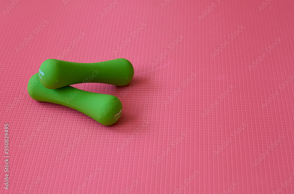 green round dumbbells on a textured pink background green round dumbbells on a textured pink background