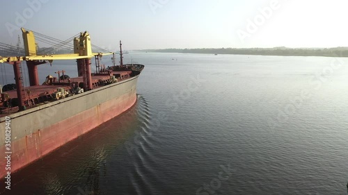 Cargo boat loaded with dry freight bulk commodities. Bulker sailing river, dispatch seaport to transfer coars grain, ore, coal. Logistic ship at daytime, close view container bulk carrier with wheat photo