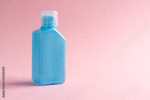 Alcohol antiseptic for hands in a blue plastic pocket container on a pink background. Copyspace. The idea of disinfection against coronavirus