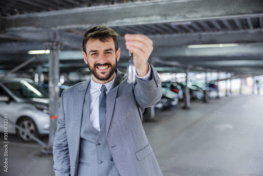 Young smiling handsome man in suit just bought a car and showing his keys. Young smiling handsome man in suit just bought a car and showing his keys.