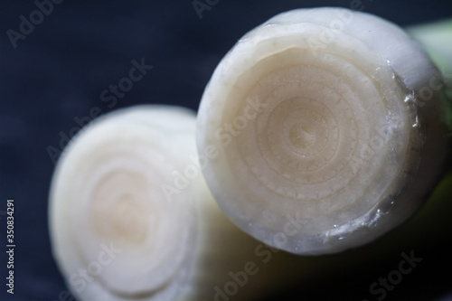 cut view of a white young onion. Close-up on a dark background