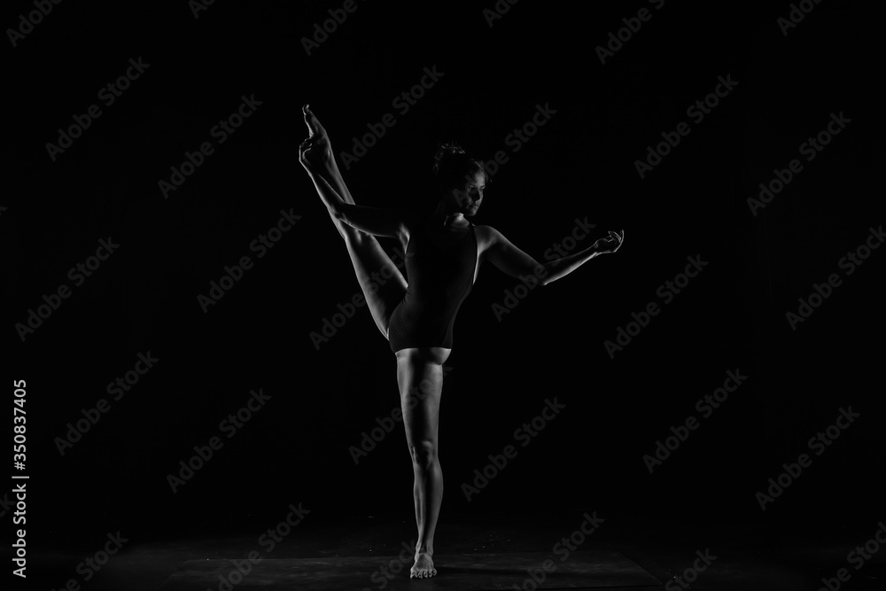 Girl yogi performs exercises on a black background. The flexibility of the female body. Asana. Relief of the muscles. Figures from the body. Girl yogi performs exercises on a black background. The flexibility of the female body. Asana. Relief of the muscles. Figures from the body.