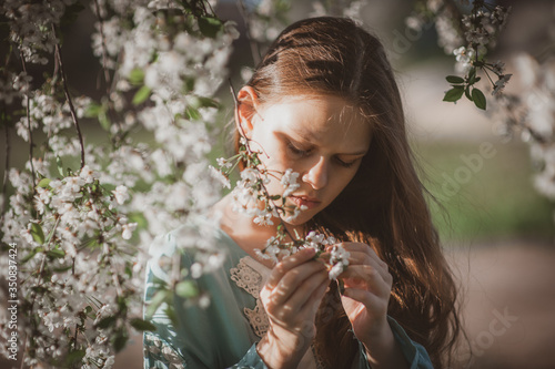 beautiful young girl with long flowing hair in a blooming cherry blossoms garden