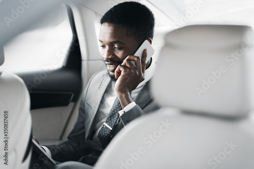Businessman Talking On Cellphone Sitting On Back Seat In Automobile © Prostock-studio