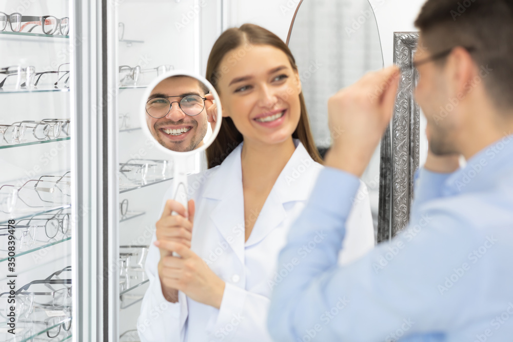 Optometrist helping man to choose correction glasses Optometrist helping man to choose correction glasses