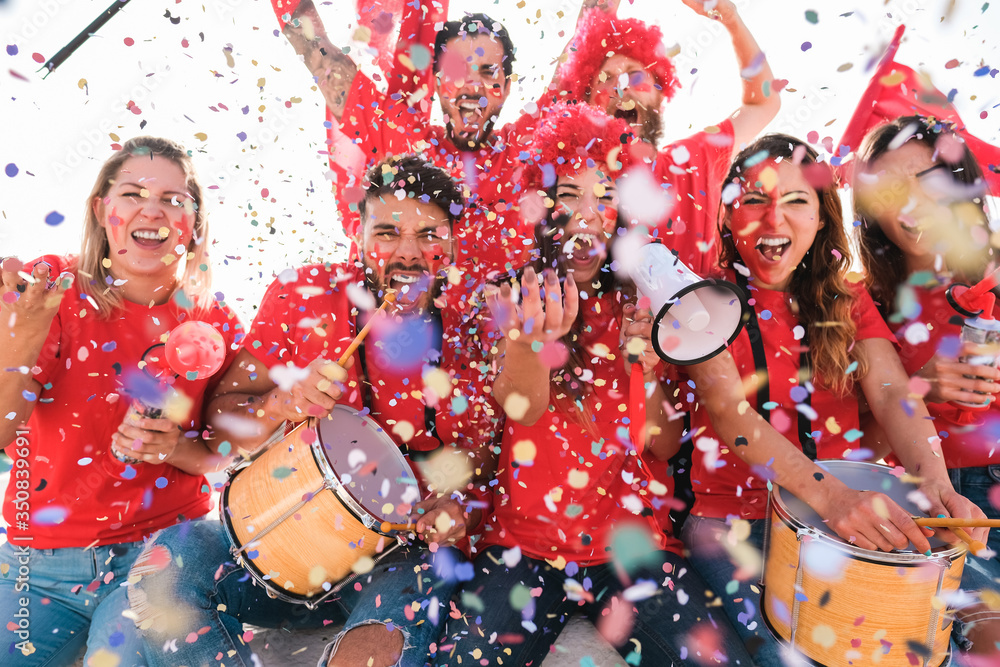 Football supporter fans cheering with confetti watching soccer match