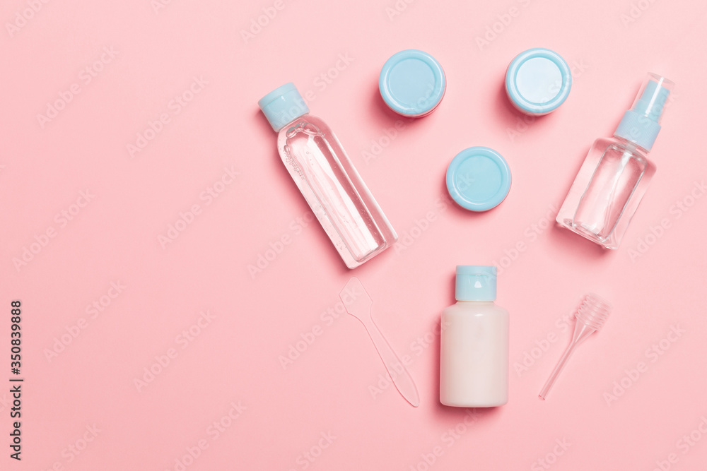 Set of travel size cosmetic bottles on pink background. Flat lay of cream jars. Top view of bodycare style concept Set of travel size cosmetic bottles on pink background. Flat lay of cream jars. Top view of bodycare style concept