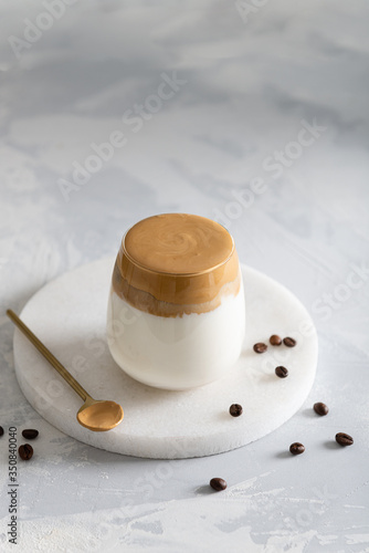 Iced Dalgona Coffee  a trendy fluffy creamy whipped coffee in a glass on white background with coffee beans. Side view  copy space. Cafe menu