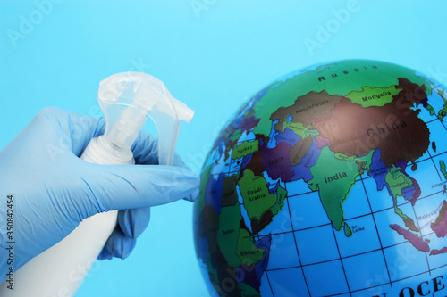 The process of disinfection of the globe, planet earth with a gloved hand with a sanitizer. Coronavirus prophylaxis.