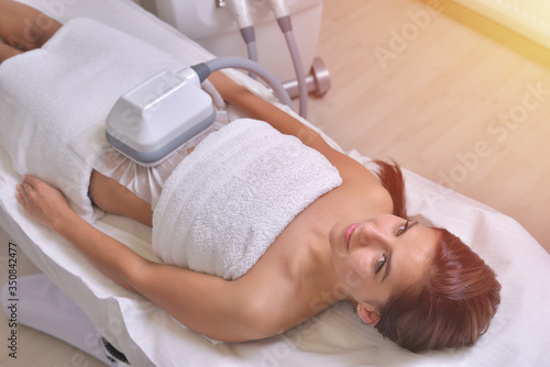 Beautiful young woman getting cryolipolyse treatment in cosmetic cabinet photo