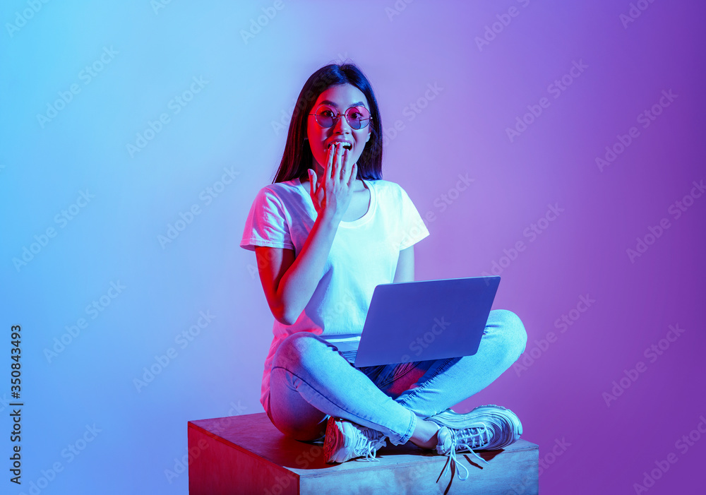 Modern blogger with laptop in workspace. Surprised girl in glasses closes mouth with hand Modern blogger with laptop in workspace. Surprised girl in glasses closes mouth with hand