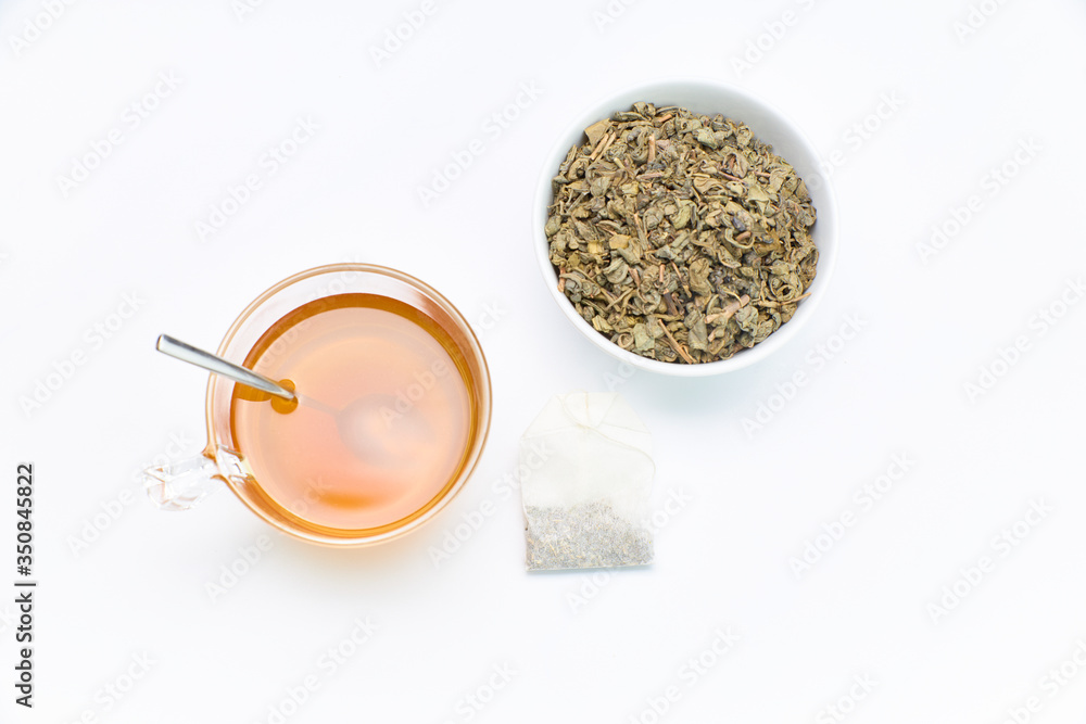 cup of green tea together with a bag and a bowl of crushed tea cup of green tea together with a bag and a bowl of crushed tea