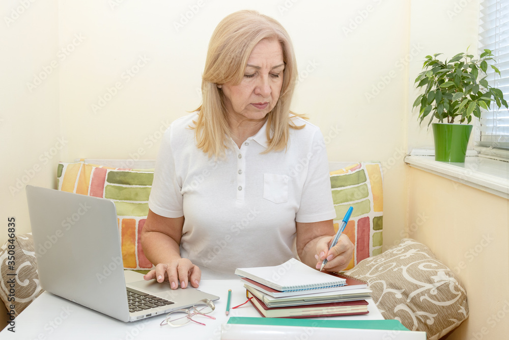 Mature woman working in a home office at a laptop. Online education for adults. Mature woman working in a home office at a laptop. Online education for adults.
