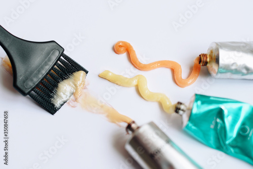 Squeezed out tubes of hair dye and brush on a white background