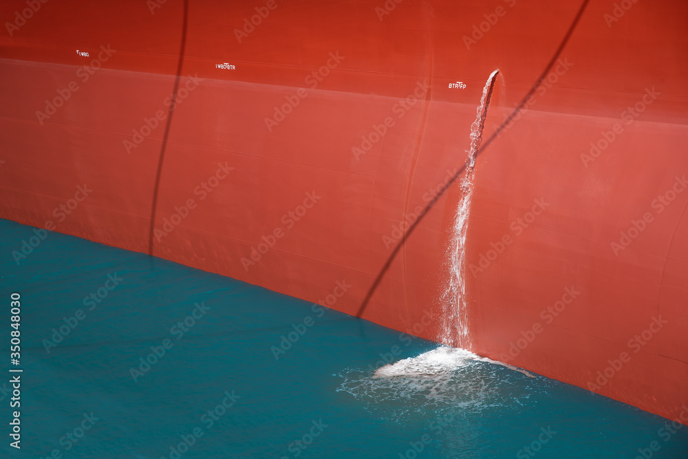 Close up Cargo ship moored in shipyard With effluent flowing beside the boat.