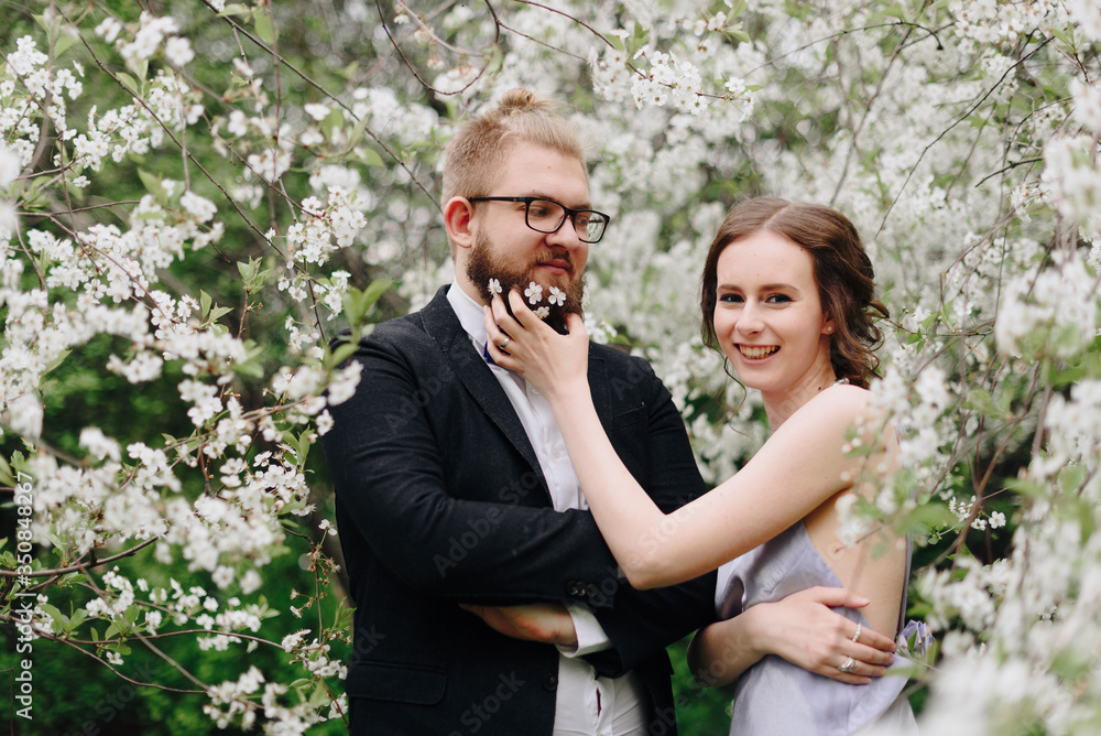 young beautiful couple in the garden against the background of cherry blossoms