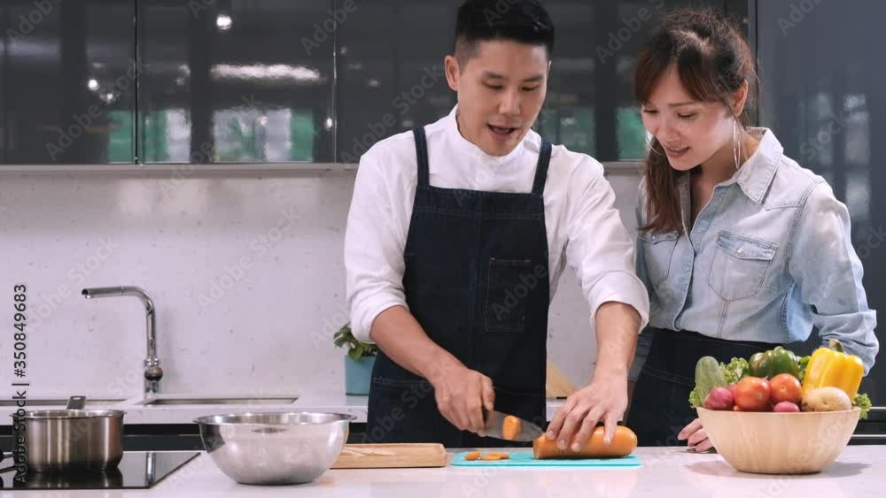 Male chef teaching young woman to practice cutting carrot in the kitchen. Male chef teaching young woman to practice cutting carrot in the kitchen.