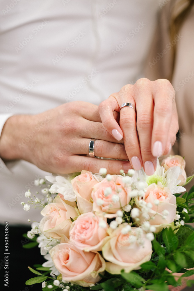 The joined hands of the bride and groom at a wedding. Wedding rings on the fingers of the newlyweds. Hands close up. The joined hands of the bride and groom at a wedding. Wedding rings on the fingers of the newlyweds. Hands close up.