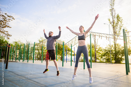 caucasian male with his personal coach young sporty female exercising outdoors in the morning. Healthy active lifestyle concept.