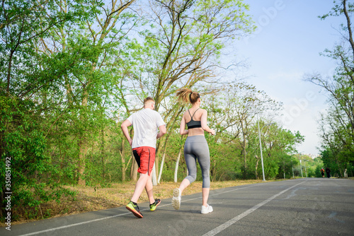 caucasian male with his personal coach young sporty female running outdoors in the morning. Healthy active lifestyle concept.