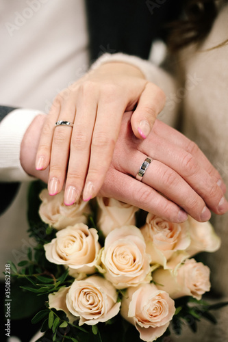 The joined hands of the bride and groom at a wedding. Wedding rings on the fingers of the newlyweds. Hands close up. 