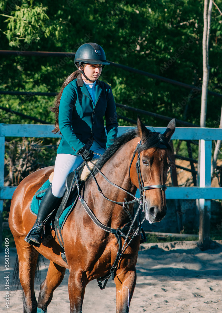 Fototapeta premium young georgian woman riding horse. Horse riding training on hippodrome
