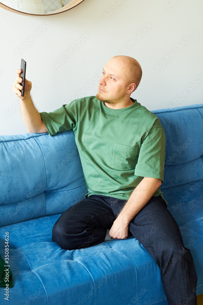 Man holding a smartphone as if making selfie in a living room Man holding a smartphone as if making selfie in a living room