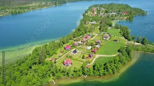 Flying over the beautiful green lanscape and houses by Lake Mausz in Poland photo