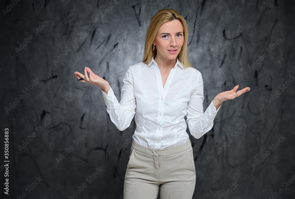 Slender Caucasian model poses in various poses. Portrait of a pretty business blonde girl in a white shirt on a gray background. Slender Caucasian model poses in various poses. Portrait of a pretty business blonde girl in a white shirt on a gray background.