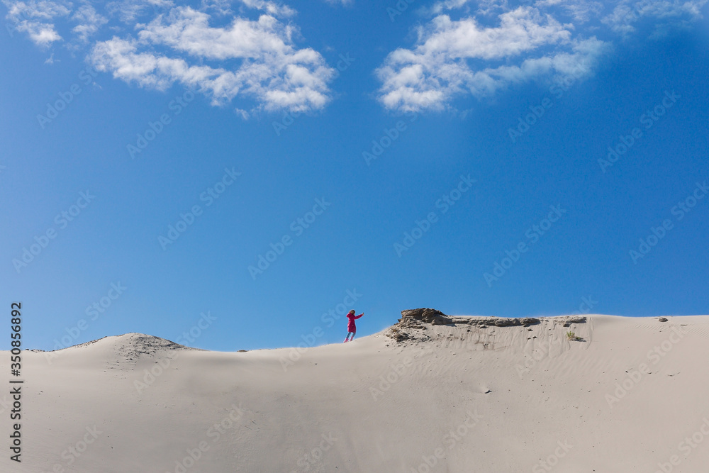 A teenager is going up to sandy stack against a clear blue sky. The stack grit, sandy mound. Concept of difficult way to the destiny. A teenager is going up to sandy stack against a clear blue sky. The stack grit, sandy mound. Concept of difficult way to the destiny.