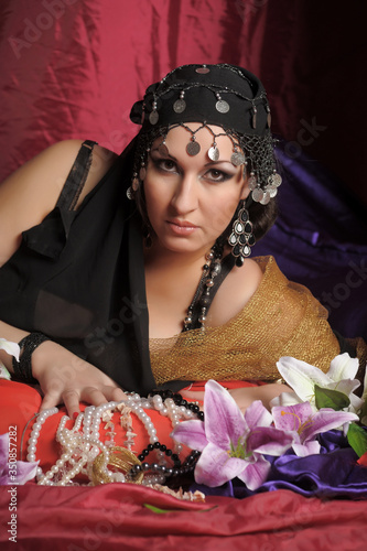 eastern woman in black clothes lies on pillows photo