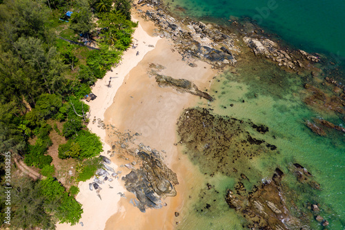 Aerial view of a beautiful, empty tropical beach surrounded by lush green foliage