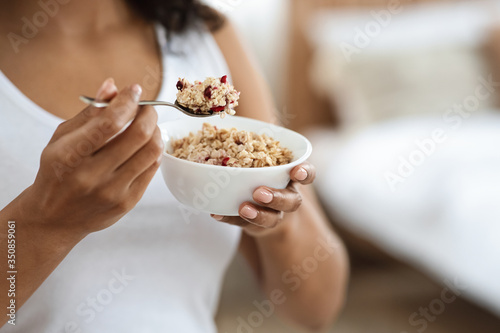 Healthy Meal Concept. Unrecognizable black woman eating oatmeal with fruits for breakfast