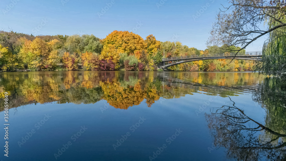 Autumn panorama with a view of the bridge and trees and reflection in the river in the Zhuravlevsky Hydropark of Kharkov
Autumn panorama with a view of the bridge and trees and reflection in the river in the Zhuravlevsky Hydropark of Kharkov