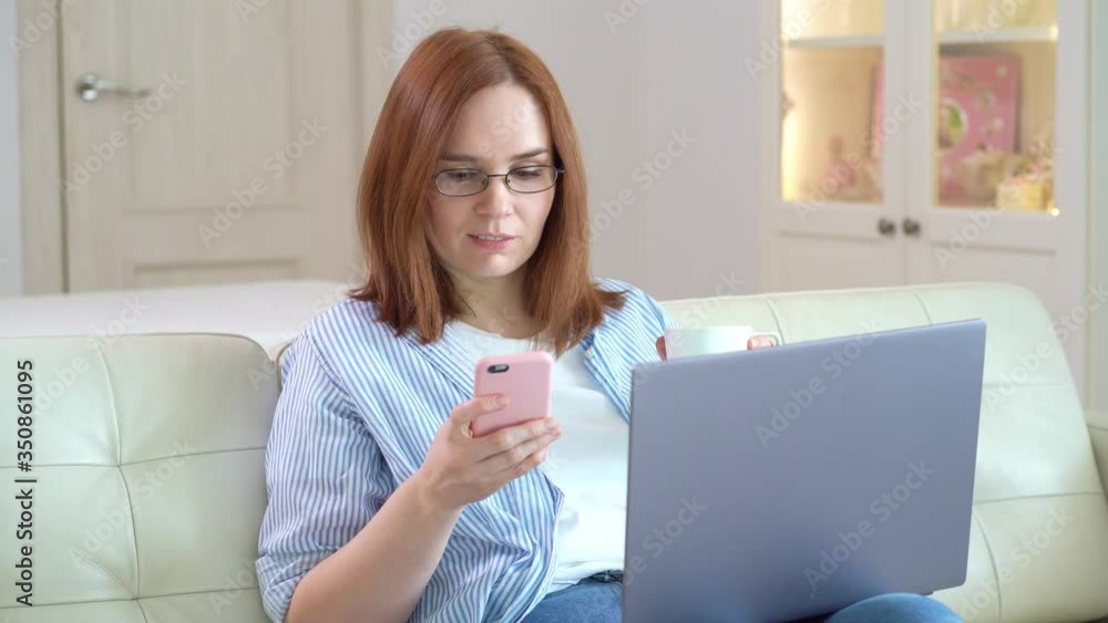 freelancer woman working at computer, drinks tea and writes message to phone. freelancer woman working at computer, drinks tea and writes message to phone.