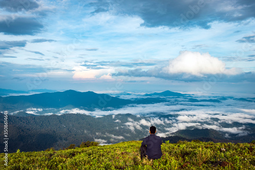 man isolated feeling the serene nature at hill top with amazing cloud layers in foreground